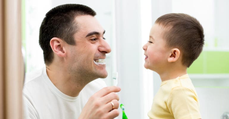 Dad and son brushing teeth together