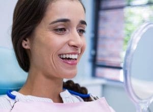 local dentist | patient smiling while looking at mirror.