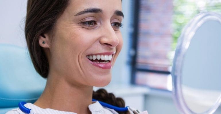 local dentist | patient smiling while looking at mirror.